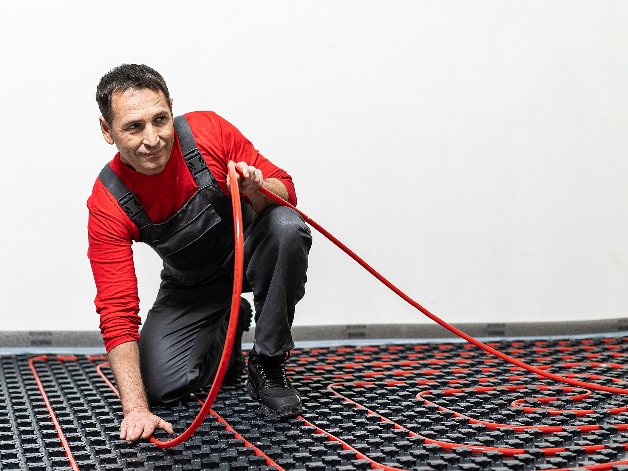 Специалист монтирует теплый пол